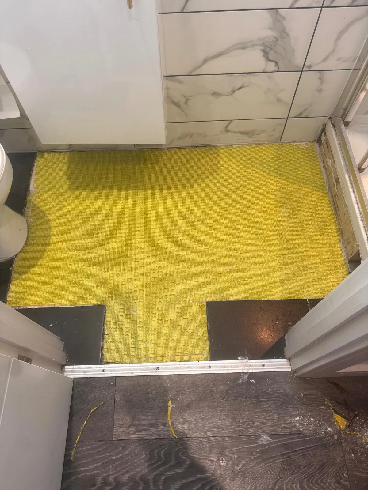 Uncoupling membrane laid over the repaired boards. This is the step that stops tiles cracking later, and it is the one most often skipped.