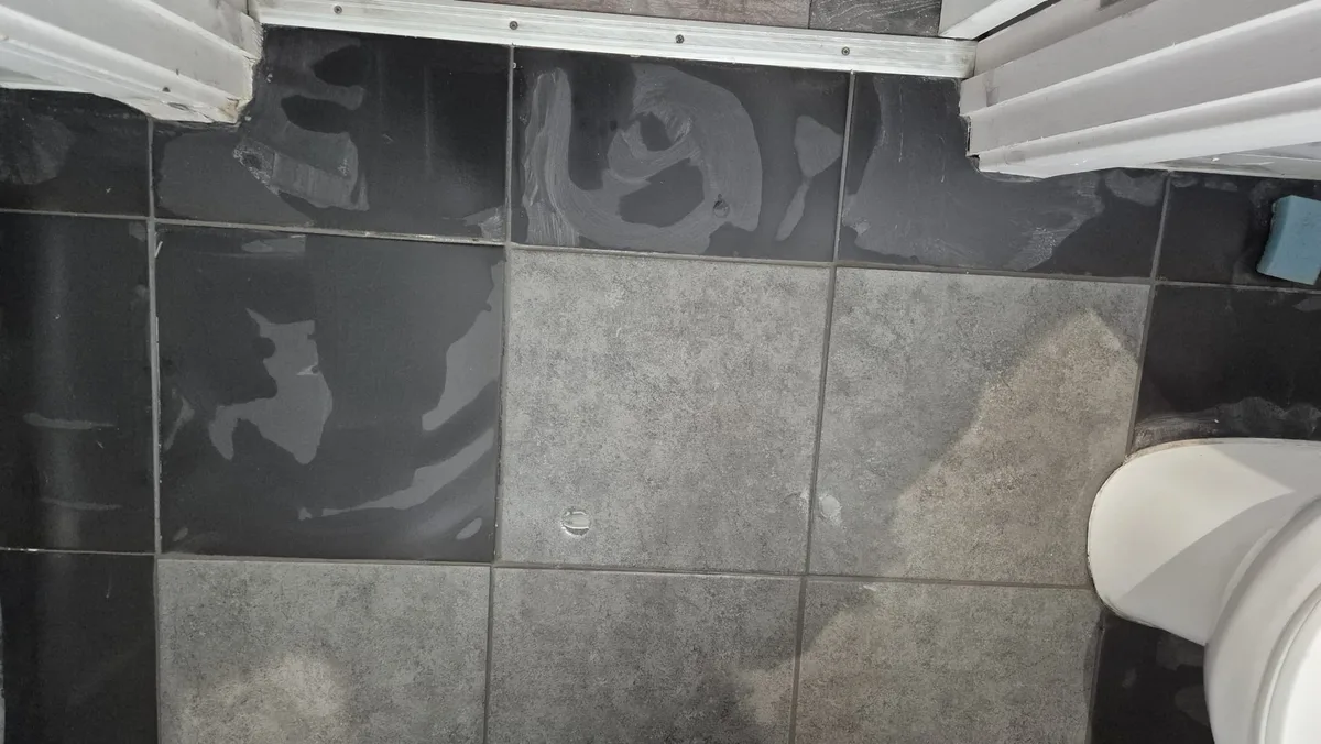 Retiled and grouted, matched to the existing dark tiles.