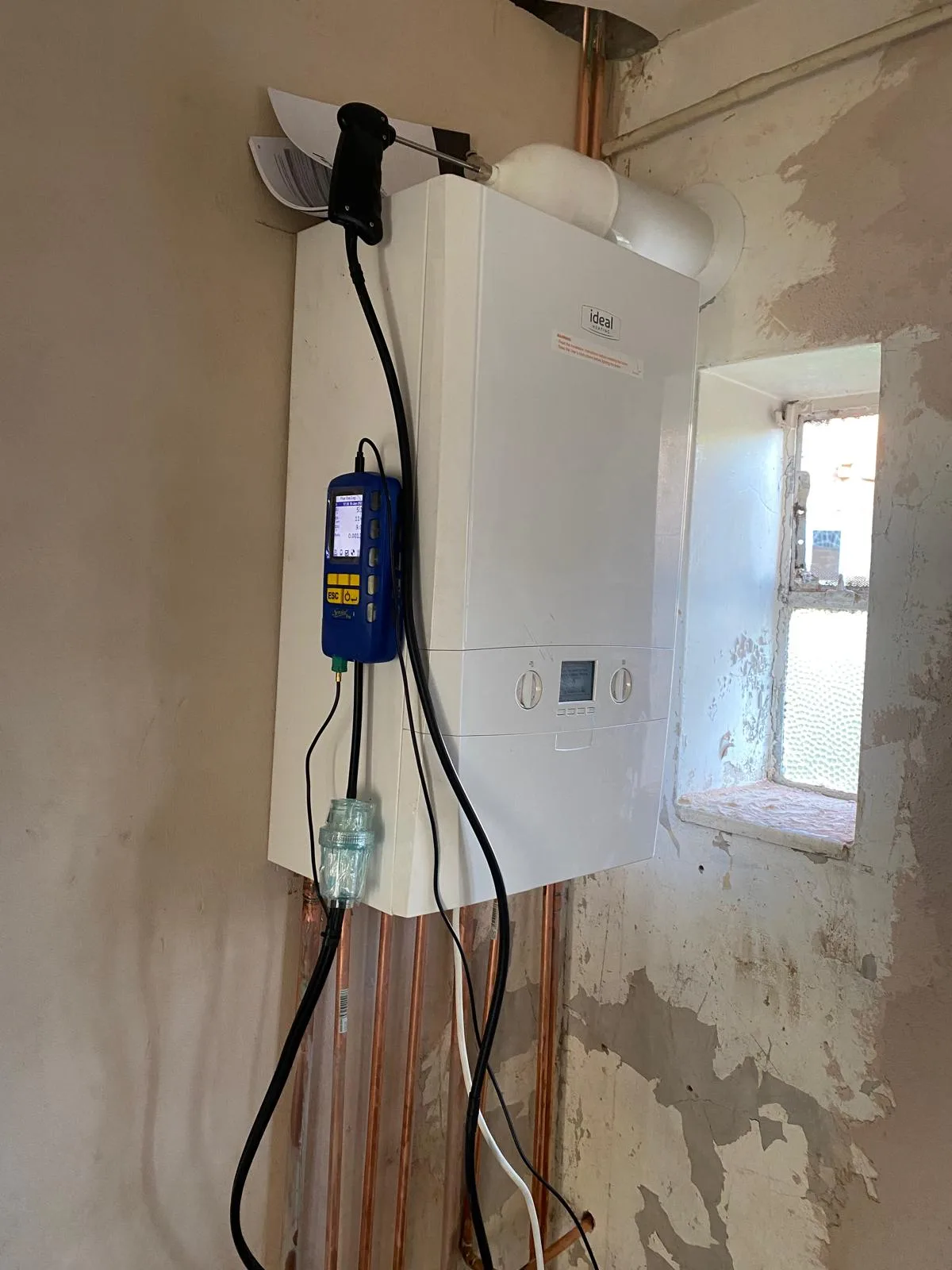 Commissioning: flue gas analyser connected with the probe in the test point. Every install gets this before it is signed off.