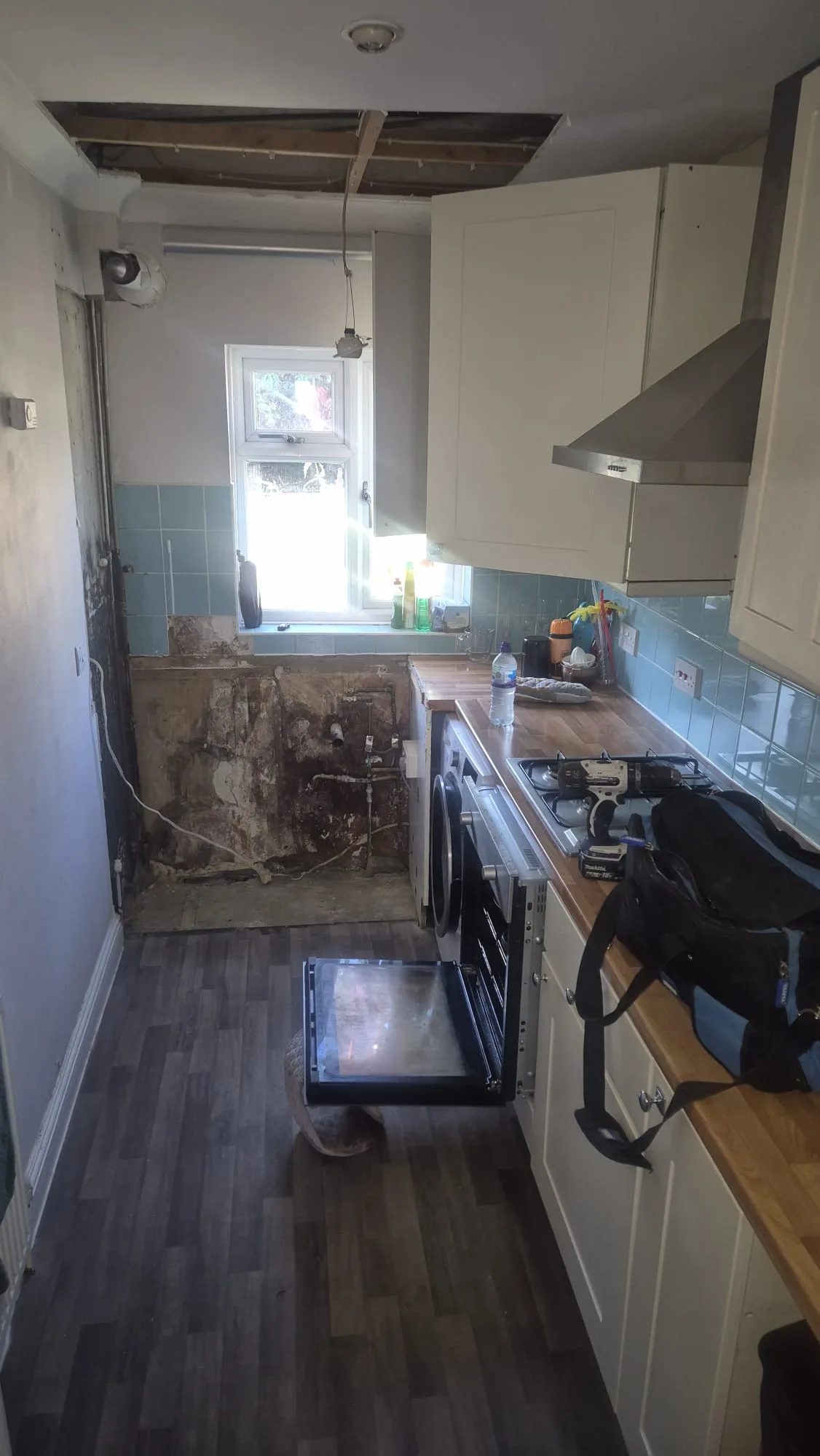 Kitchen mid-strip with the ceiling opened to the joists to take new pipework.