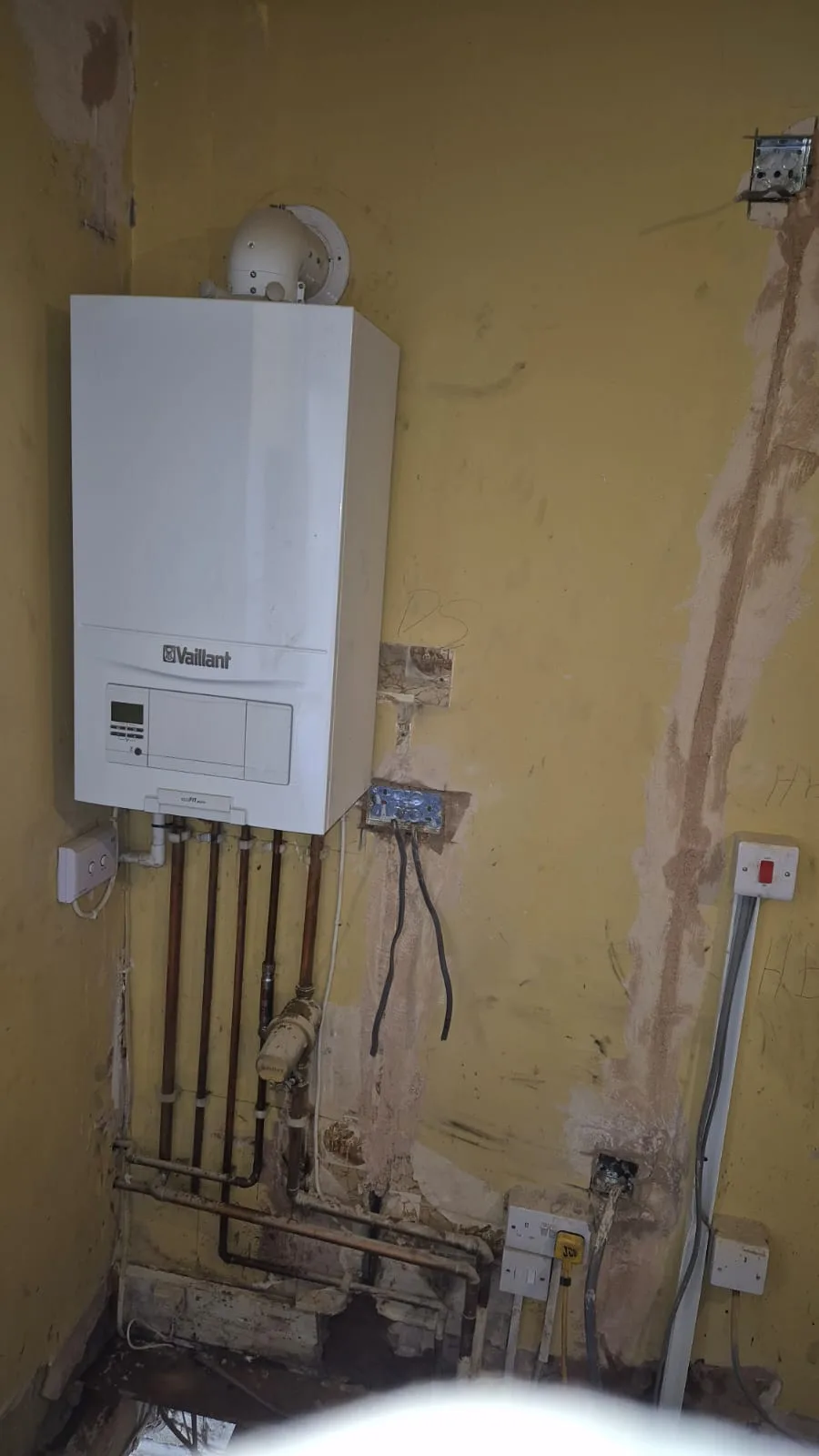 New Vaillant ecoFIT pure in place, flue elbow on top, new copper tails and condensate trap below.