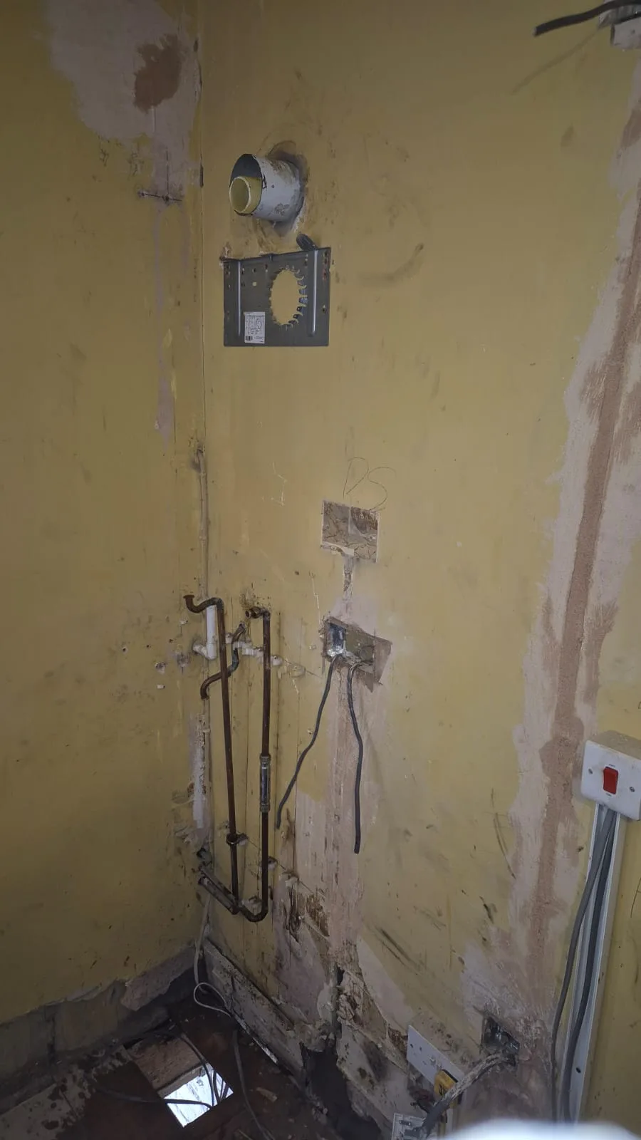 Old boiler removed — bare bracket, flue hole with its sleeve, capped copper tails and chased-out back boxes.